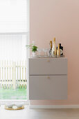 Minibar on grey-painted floating cabinet on pink wall