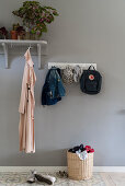 Coat rack and row of hooks on grey wall in foyer