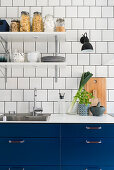 Küche mit blauen Fronten und weißen Fliesenwänden