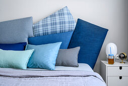 Cushions in shades of blue on double bed and bedside table in bedroom