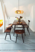 Dining table, stool, chair and bench below sloping ceiling