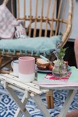 Sandwiches, coffee cups, magazines and vase of flowers on folding table outside