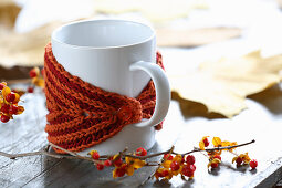 Rusty-red hand-knitted mug warmers for decorating autumnal table