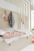 Girl's bedroom in beige and pink with bed below canopy of wooden slats