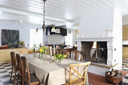 Large country-house kitchen-dining room with dining table next to open fireplace