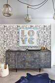 Nursery with rabbit wallpaper and 'Love' motto on wall above grey dresser