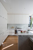 White, modern kitchen with marble island counter