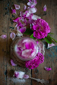 Pinkfarbene Rosenblüten mit Zucker im Schraubglas