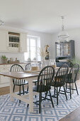 Dining table and dark chairs on rug in country-house kitchen