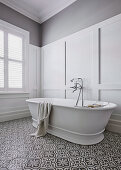 Freestanding bathtub in front of coffered wall in classic bathroom