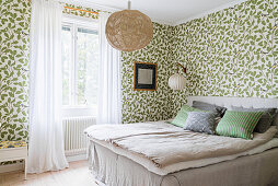 Double bed and leaf-patterned wallpaper in guest bedroom