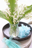 Posy of lily-of-the-valley and paper flowers in flan tin