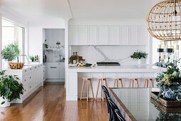 White kitchen with counter and dining area, splash protection in marble look