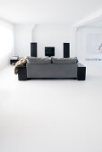 Graues Sofa im minimalistischen Wohnzimmer mit weißem Boden