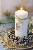 White candle with pine cones on a silver tray