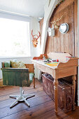 Vintage-style swivel chair made from wooden boards and bureau in room with wooden wall