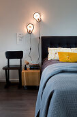 Doppelbett mit schwarzem Bettkopfteil und Wandleuchten im Schlafzimmer