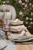 Stoffservietten mit einer Rose auf dem gedeckten Tisch im Garten