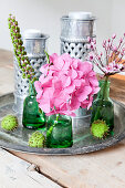 Grüne Fläschchen mit Blumen und Teelichthalter aus Metall auf Vintage Tablett