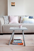Scatter cushions on pale grey sofa and stool used as small table in living room