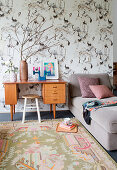 Retro desk with stool and couch against bird-patterned wallpaper