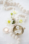 White wooden bead necklace, flowers and Christmas decorations on table