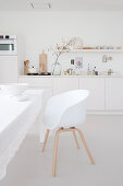White shell chair at table with white tablecloth in kitchen-dining room with white kitchen counter