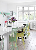 Colorfully painted chairs at a table in a white dining room