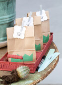 Paper bags with gift tags and crowns on a red metal tray