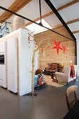 Comfortable armchairs and wood panelling in festively decorated seating area in open-plan interior