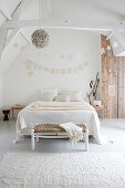 A double bed in a white bedroom with wooden accents