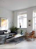 Graues Sofa und Lederstuhl im schlichten Wohnzimmer mit weißem Boden