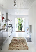 A rug on a white wooden floor in front of a kitchenette