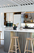 Bar stools at a kitchen island with a stainless front in a modern kitchen