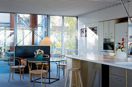 Bistro chairs at a round glass table in front of an open-plan kitchen