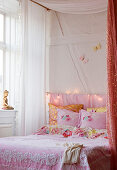 Romantic pink bed linen in the four-poster bed