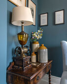 Old stoneware jugs and lamp on little old table against blue walls
