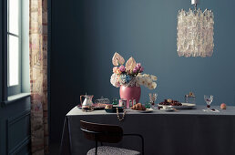 Feminine breakfast table with bouquet and jewelry, designer chandelier above