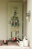 Organiser and utensils hung on inside of back door and basket of flowers on floor