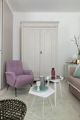 Tischchen, lila Sessel und weißer Holzschrank im Wohnzimmer