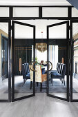 Open double doors in glass wall leading into elegant dining room