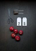 Ribbon, numbered card, red apples and scissors on dark surface
