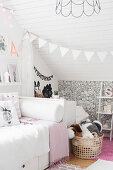 Bed in girl's bedroom with sloping ceiling and patterned wallpaper on knee wall