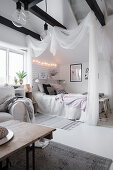 Bett mit Baldachin im Dachzimmer in Weiß mit schwarzen Deckenbalken