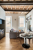 Kleiner Wohnraum mit Sofa, rundenm Esstisch und verschließbarer Schrankküche