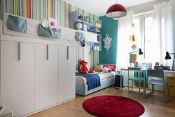 Loft bed and multicoloured striped wallpaper in sibling's bedroom