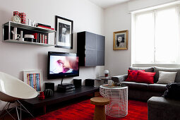 Black furniture and red accents provided by rug and cushions in living room