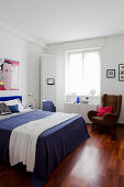Bedroom with white walls, Pop-art picture on wall and blue bed