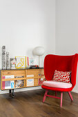 Red armchair providing a splash of colour and retro sideboard in reading area