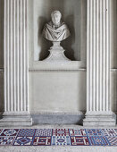 Moderne Fliesen mit geometrischen Mustern vor antiker Büste zwischen Säulen